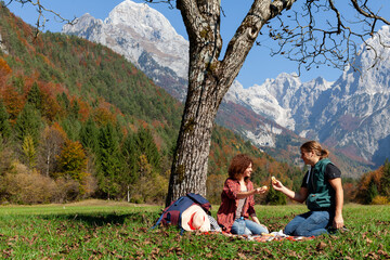 Mid Adult Couple Pausing for a Meal Break During Their Mountain Journey Beneath a Tree in an Awe-Inspiring Setting
