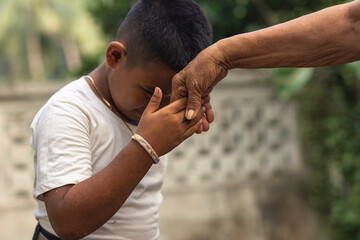 A respectful boy does the mano po gesture to his grandmother. A sign of respect and reverence to...