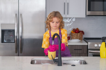 Portrait of child cleaning in the kithen. Child housekeeper washing the dishes on soapy water. Cute Funny boy washing dishes in kitchen. - obrazy, fototapety, plakaty