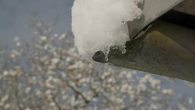snow melting from gutter in winter with sun shining