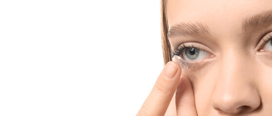 Young woman putting in contact lenses on white background, closeup. Banner for design