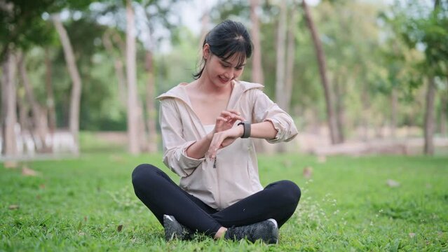 An Asian woman in workout attire is exercising with the smartwatch's fitness function in a public park. Capture the blend of technology and outdoor fitness for a vibrant image.