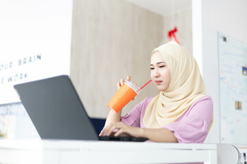 Asian Muslim woman wearing hijab working at office with documents on table, planning to analyze financial report, business plan, investing, financial concept and having fun at work