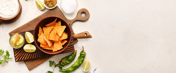 Bowl with tasty nachos and sauces on light background with space for text