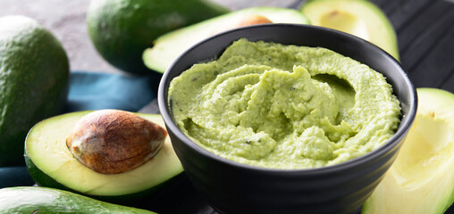 Bowl with delicious guacamole on table, closeup