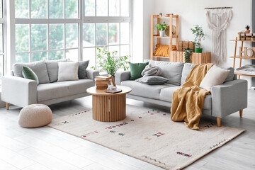Interior of light living room with stylish grey sofas and wooden coffee table