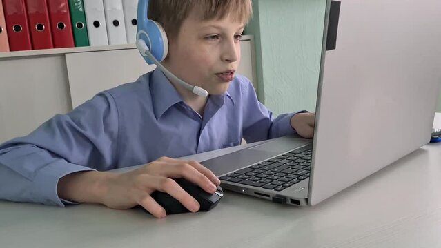 Computer gamer teenager guy in headphones playing computer games and communicating live in room. Generation z teenage boy using laptop for Sports or virtual sports