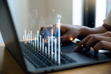 Businessman using laptop with graph growth analysis on virtual screen, Growing revenue and Financial 2019 to 2024 concept. - 697477449