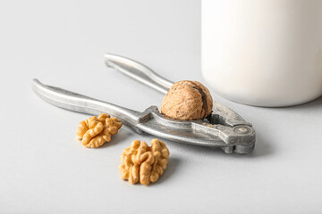Nutcracker with tasty walnuts on grey background