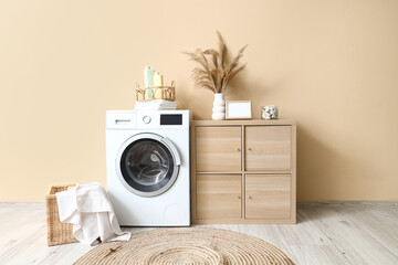 Laundry room interior with washing machine, towel in wicker basket and wooden cabinet