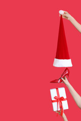 Many hands with Christmas hat, gift box and shoe on red background