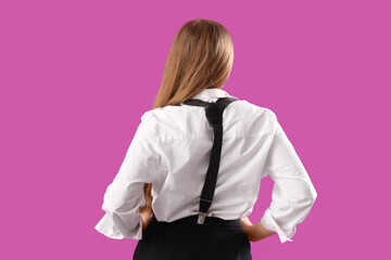 Stylish young woman with suspenders on purple background, back view