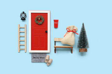 Beautiful composition with door, ladder, Christmas tree and decorations on blue background