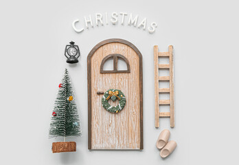 Beautiful composition with door, ladder, Christmas tree and decorations on grey background