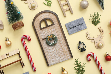 Beautiful composition with door, ladder, Christmas tree, candy cane and decorations on yellow background