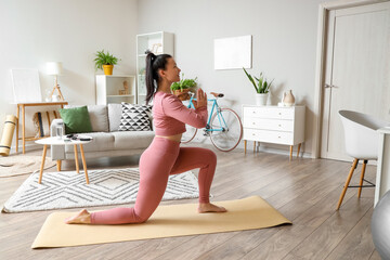 Sporty young woman doing yoga on mat at home