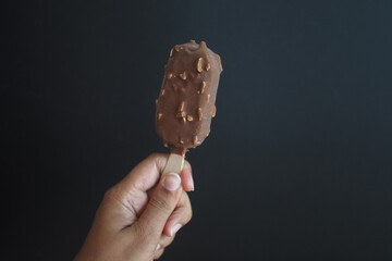  person hand holding ice cream against black background 
