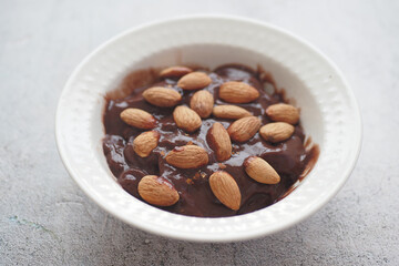dark chocolate cream pouring on almond nut on white 