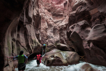 Extreme tourists walk along the Mujib River, flowing between high cliffs along the tourist route in the Mujib River canyon in Wadi al-Mujib in Jordan