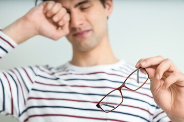 Young man with eyeglasses on light background, closeup. Glaucoma awareness month