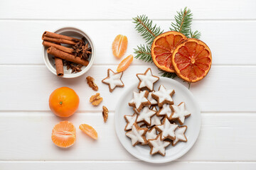 Fototapeta na wymiar Composition with delicious stars shaped Christmas cookies, orange dried pieces, mandarins, spices and fir tree branch on light wooden background