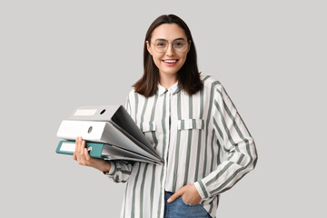 Young businesswoman with document folders on light background