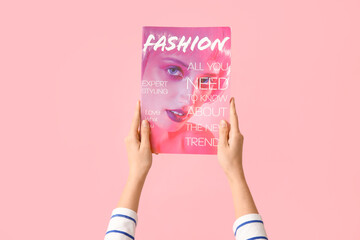 Young woman with fashion magazine on pink background