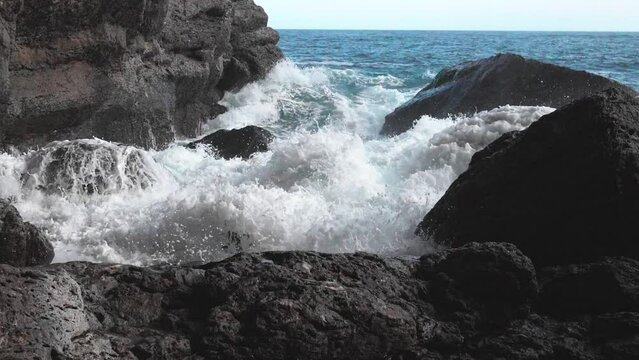 Slow motion. Brightly turquoise waves break into white foam on the coastal cliffs and seethe between them. The need to protect the environment. Ecology and global warming