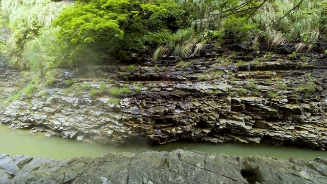 Cinematic gimbal shot of forest trail leading to steam vents at Oyasukyo Gorge in Akita prefecture in Japan