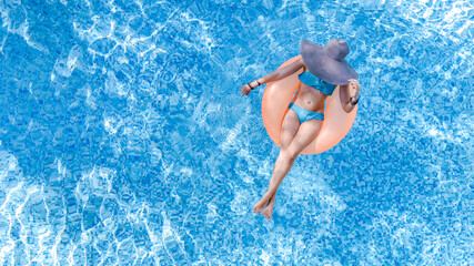 Beautiful woman in hat in swimming pool aerial drone view from above, young girl in bikini relaxes...