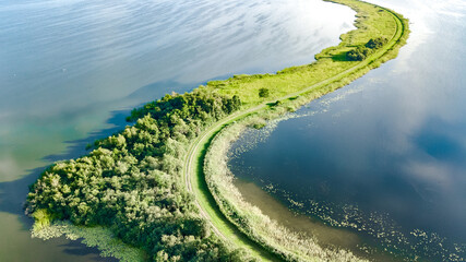 Aerial drone view of path on dam in polder water from above, landscape and nature of North Holland,...