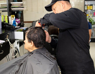 a senior male hairdresser cutting the hair of a senior adult woman
