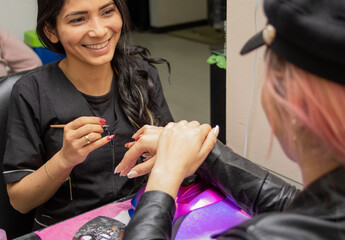 a female stylist fixing the nails of a beautiful young woman