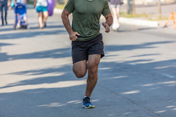 A man in shorts runs along the road in the city. Sport