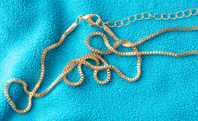 Gold chain on blue fabric. Close-up