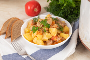 Beef, meat, stewed with potatoes, carrots, tomatoes and spices in modern multi cooker on kitchen table. Cooking stewed potatoes with meat in multicooker.