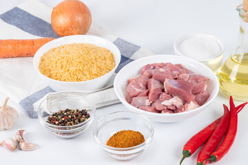 Prepared ingredients for cooking pilaf in modern multi cooker in kitchen on a table. Cooking pilau with meat in multicooker.