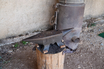 old heavy metal anvil on a wooden stump in ancient farm