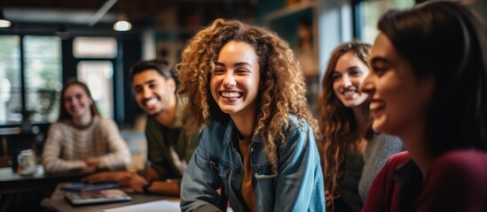 College students from different backgrounds gathering at a table in the classroom for a group activity.