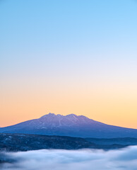 朝焼けの空の下、雲の向こうに遠くの山の稜線。