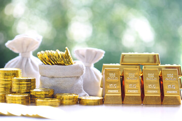 Gold bars and stack of gold coin money in a bag on natural green background,Business investment and...