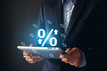 Businessman hands holding digital tablet with percentage symbol on dark background, Interest rate and business investment concept