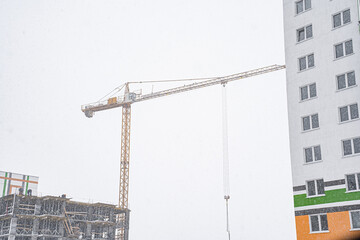 Construction of a monolithic house in winter with the help of a tower crane during falling snow