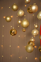 New Year's golden balls hanging on strings on background with mirror in the form of a large window