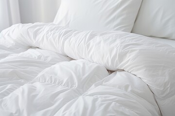 Fototapeta na wymiar White folded duvet lying on white bed background