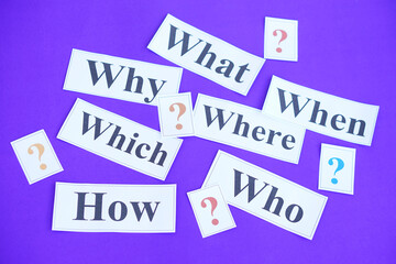 Paper cards with Wh-question words and question marks on purple background. Concept. Teaching aid. Education materials for teach WH- question. Asking questions. Suspicious symbol to find answer.      