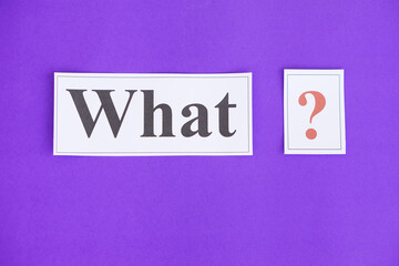 Paper cards with text  What and question marks on purple background. Concept. Teaching aid. Education materials for teach WH- question. Asking questions. Suspicious symbol to find answer. 