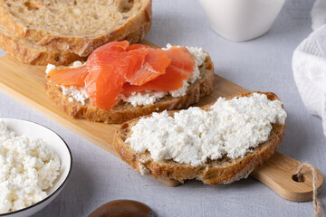 Sandwich with salted salmon and cottage cheese on a wooden table - obrazy, fototapety, plakaty