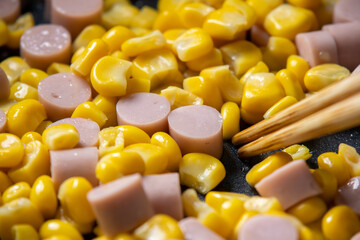 魚肉ソーセージと粒コーンを炒める調理シーンのアップ。
