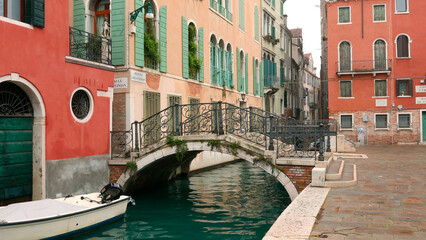 Fototapeta na wymiar Venice picturesque small bridge 'Ponte Giustinian' and buildings with attractive complementary red and green colors.